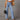 Woman wearing light blue high-waisted flared jeans in 70s style with a focus on denim fabric.