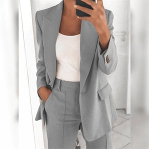 Woman wearing a tailored blue blazer and high-waist pants suit, standing against a neutral background, showcasing the professional outfit.