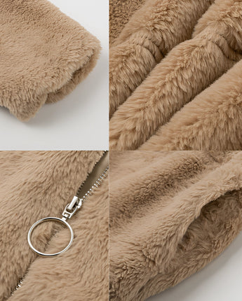A beige teddy jacket made of soft fleece, featuring a high collar, modeled with a close-up showing part of a hand wearing a fashion accessory, emphasizing the jacket's plush texture.