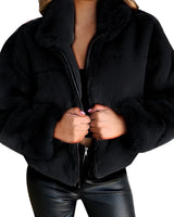 Black teddy jacket made of soft fleece material featuring a zip-up front and high collar, modeled by a person wearing it, showcasing the sleeves and waist area.