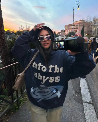 Oversized blue camouflage hoodie worn by a woman standing outdoors, featuring sunglasses and casual streetwear style.