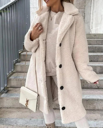 
A woman wearing a long brown teddy coat styled for winter, showcasing its fashionable design with an apricot hue in an XXL size. The coat features a collar and long sleeves, standing out with its outerwear appeal.
