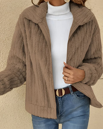 A woman wearing a cozy, brown teddy jacket with a fleece collar, paired with jeans. The jacket is suitable for autumn and winter, available in khaki color and 5XL size.