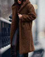 
A woman wearing a long blue teddy coat, showcasing a cozy and fashionable winter style. The coat is fluffy with a tartan pattern, covers the shoulders and knees, and features long sleeves. She pairs the coat with eyewear, adding a chic touch to her winter outfit.