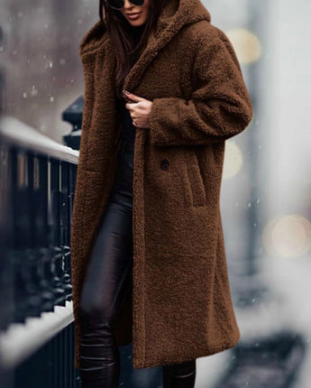 
A woman wearing a long blue teddy coat, showcasing a cozy and fashionable winter style. The coat is fluffy with a tartan pattern, covers the shoulders and knees, and features long sleeves. She pairs the coat with eyewear, adding a chic touch to her winter outfit.