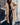 
A woman wearing a long blue teddy coat, characterized by its fluffy texture, suitable for winter fashion. The coat features long sleeves and extends to the knee, offering a cozy and stylish look. The woman is also wearing eyewear, adding a fashionable touch to her outfit.