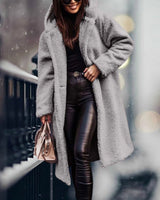 
Image of a woman wearing a long blue teddy coat designed for women, featuring a fluffy texture ideal for winter fashion. The coat is in a grey color, size XL, and includes details such as a collar, long sleeves, and a knee-length cut. The woman is also wearing eyewear.