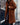Long rust-brown teddy coat for women in XL, featuring a plush, fuzzy texture, modeled standing with visible shoulders, neck, sleeves, and a knee-length hem, exemplifying stylish winter fashion.