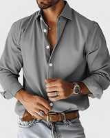 A man wearing a luxurious black slim fit silk dress shirt in a designer style, showcasing the shoulder, sleeve, and neck details.